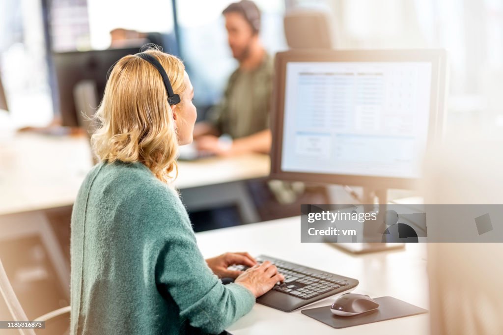 Blonde female pollster using a computer and wearing a headset