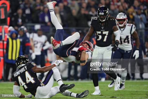 Wide receiver Julian Edelman of the New England Patriots is upended by cornerback Marlon Humphrey and linebacker Patrick Onwuasor of the Baltimore...