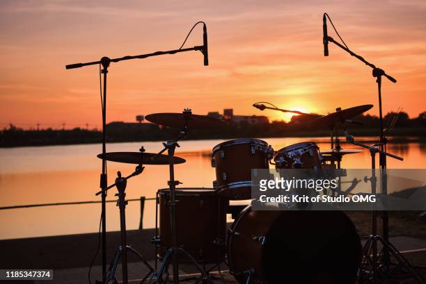 silhouette drum kit by the lake - beach music festival photos et images de collection