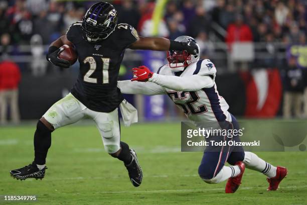 Running back Mark Ingram II of the Baltimore Ravens rushes past linebacker Elandon Roberts of the New England Patriots during the fourth quarter at...