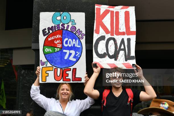 People hold up signs during a rally calling for action on climate change in front of the Liberal Party headquarters in Sydney on November 29, 2019. -...