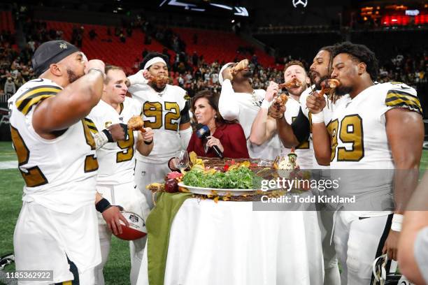 Members of the New Orleans Saints celebrate their victory with turkey legs following an NFL game against the Atlanta Falcons at Mercedes-Benz Stadium...