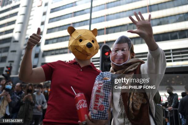 Protester wearing a Winnie the Pooh mask and one wearing a mask of China's President Xi Jinping take part in a lunchtime flash mob rally in the...