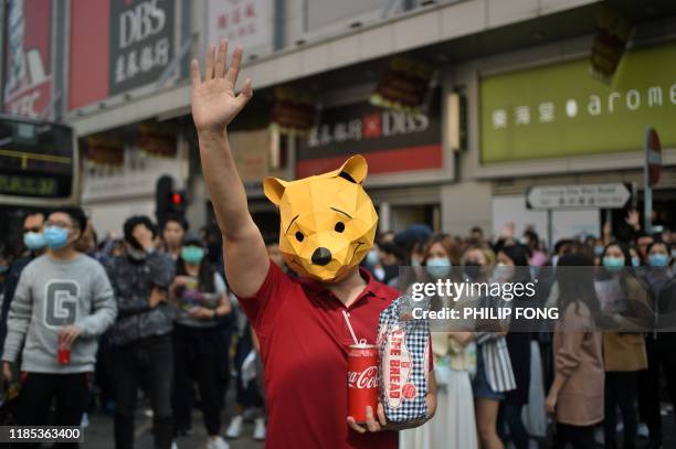 Man wears a Winnie the Pooh mask as he joins others in a lunchtime flash mob rally in the Cheung Sha Wan district in Hong Kong on November 29, 2019....