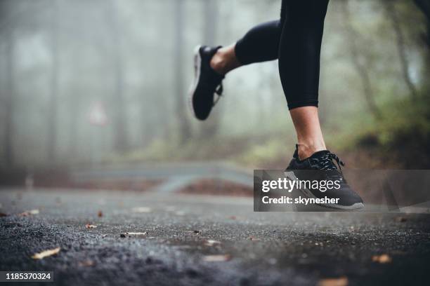 unrecognizable athlete jogging on the road during rainy day. - black shoe stock pictures, royalty-free photos & images