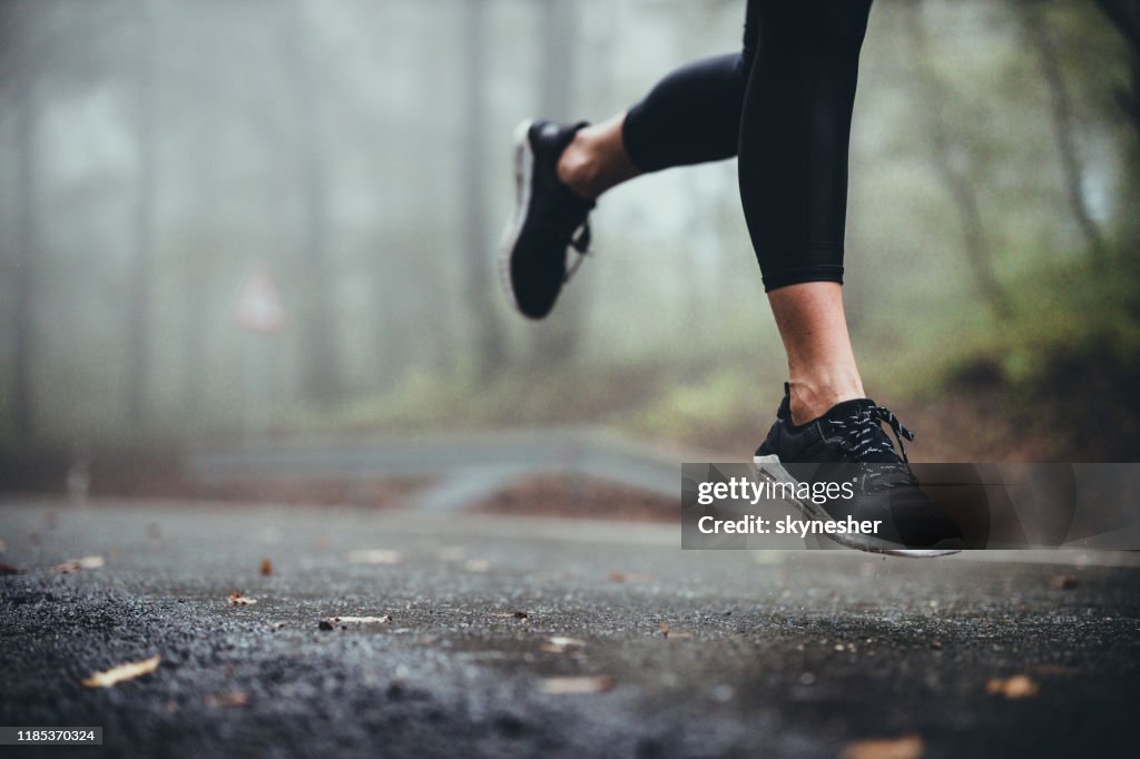 在雨天,無法辨認的運動員在公路上慢跑。