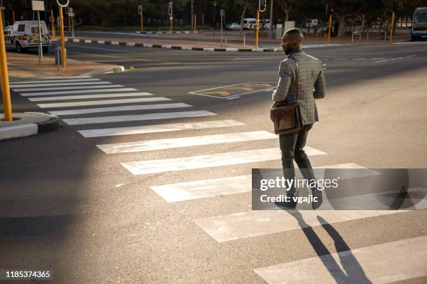 businessman crossing the street and using smart phone - pedestrian crossing man stock pictures, royalty-free photos & images