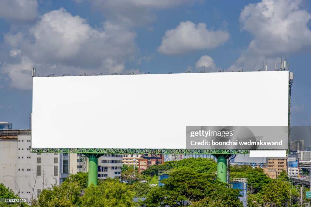 Large blank billboard on road with city view background