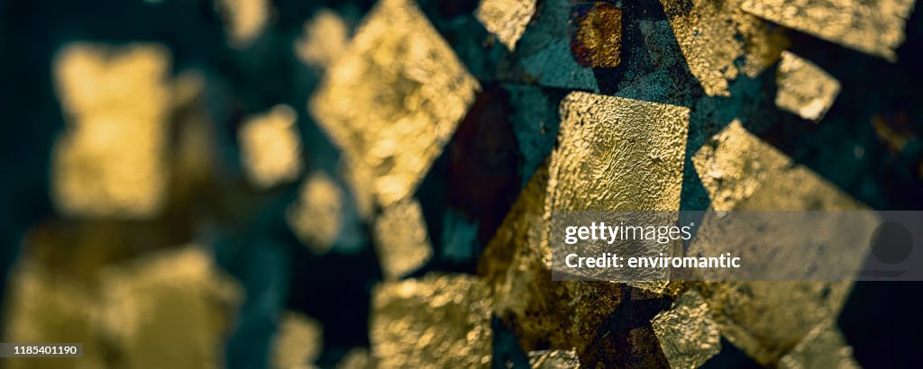 Abstract, gold leaf background on a rusty metal surface.
