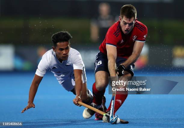 Firadus Rosdi of Malaysia battles for possession with Henry Weir of Great Britain during the Olympic Qualifier match between Great Britain and...