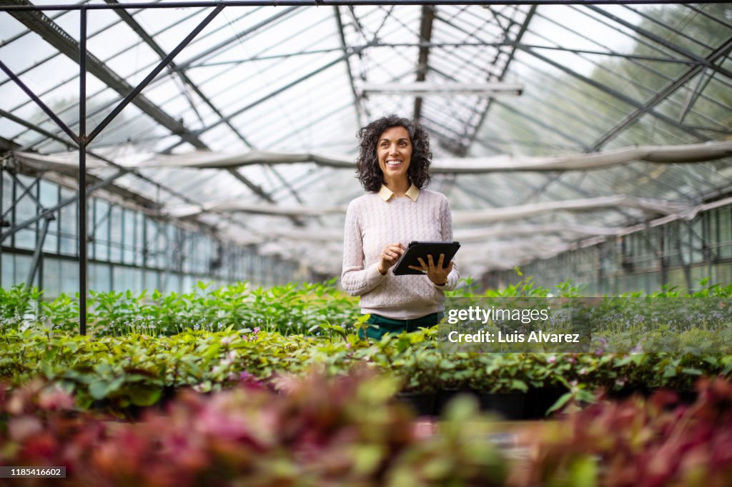 Mature woman gardener with digital tablet at garden center