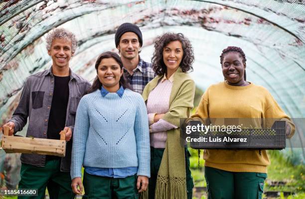 multi-ethnic garden workers standing in greenhouse - five people stock-fotos und bilder