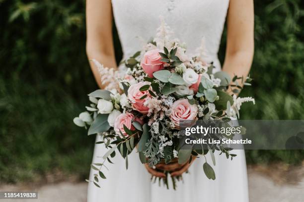 bride holding her bridal bouquet with pink roses and eucalyptus - bouquet foto e immagini stock