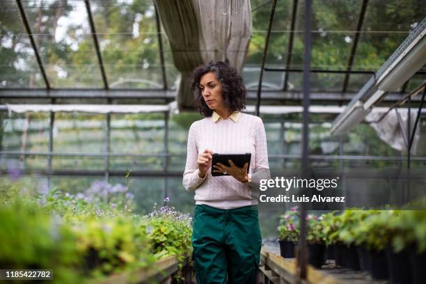 mature woman garden worker with a digital tablet - biotechnologie photos et images de collection