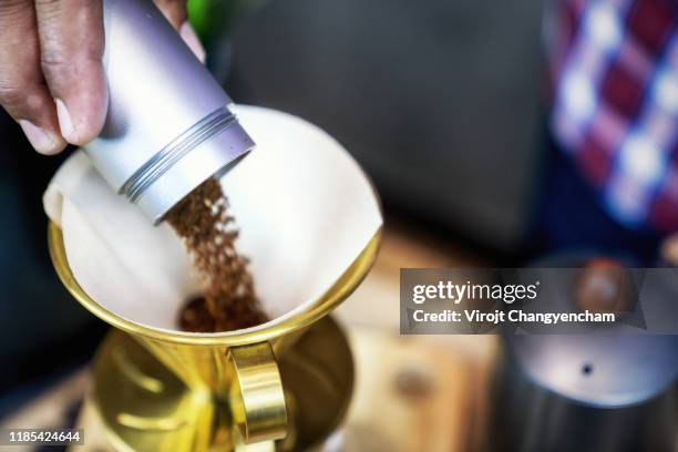 hands put bean coffee grinder powder in the paper drip before brewing coffee - moka pot stockfoto's en -beelden