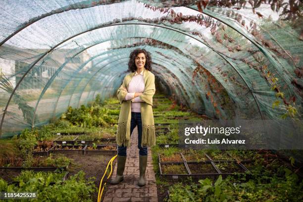 portrait of a smiling mid adult woman in greenhouse - green economy stock pictures, royalty-free photos & images