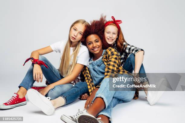 drie mooie jonge meisjes zitten in de studio - friends with white background stockfoto's en -beelden