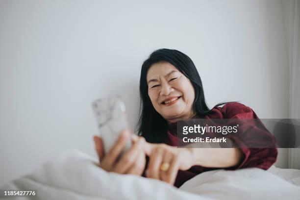 Active senior woman using phone at her home