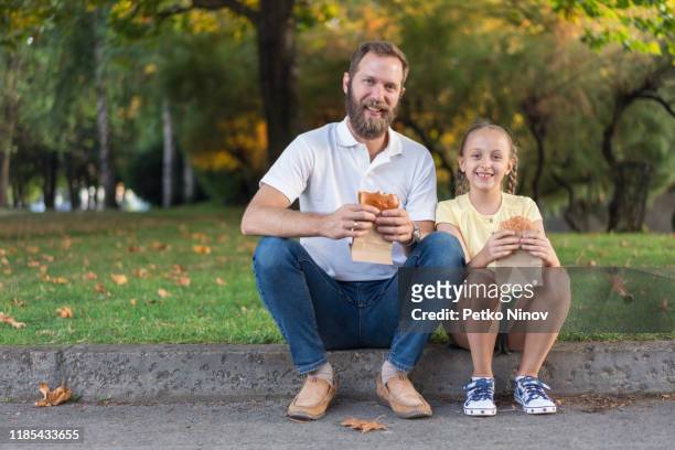 vater und tochter essen burger - girls laughing eating sandwich stock-fotos und bilder