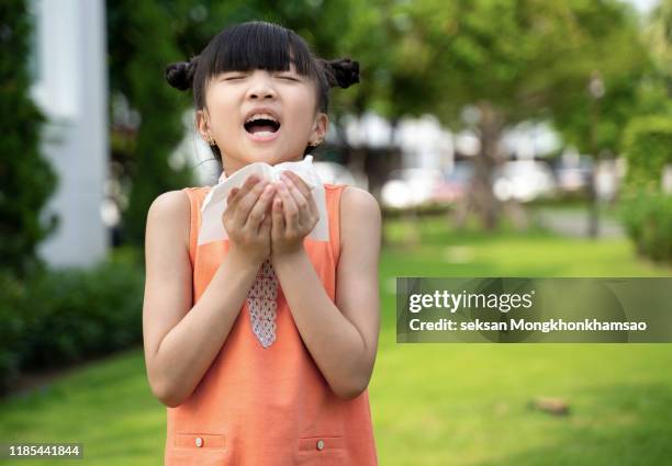 sick asian little child girl wiping and cleaning nose with tissue on her hand - sneeze stock pictures, royalty-free photos & images