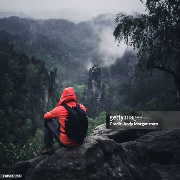 walker sitting on rocks at a rainy day - wandern regen stock-fotos und bilder
