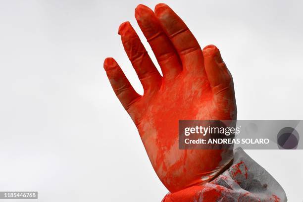 The gloved-hand of a demonstrating student, covered in red paint symbolizing the blood of slaughtered animals for human consumption, is pictured...