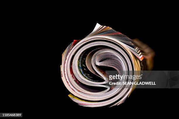 rolled up magazine on black - tabloids stock pictures, royalty-free photos & images