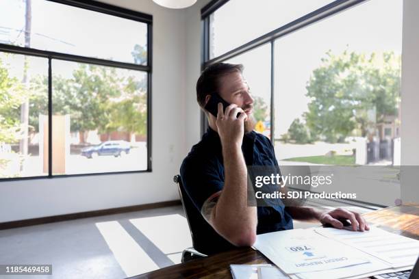 mid adult zakenman gebruikt telefoon in office - credit report stockfoto's en -beelden