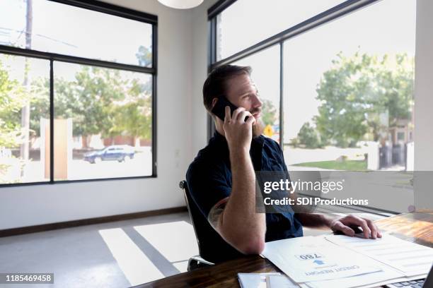 mid adult businessman uses phone in office - credit report stock pictures, royalty-free photos & images