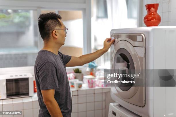 mature man operating washing machine - gas washer dryer stock pictures, royalty-free photos & images