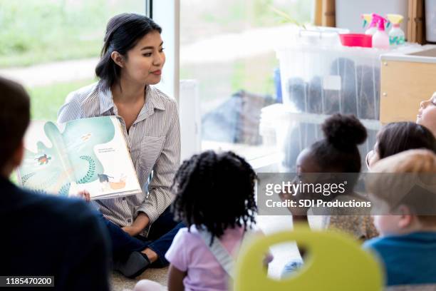 bibliotecario legge ai bambini un libro durante la storia - libro illustrato foto e immagini stock