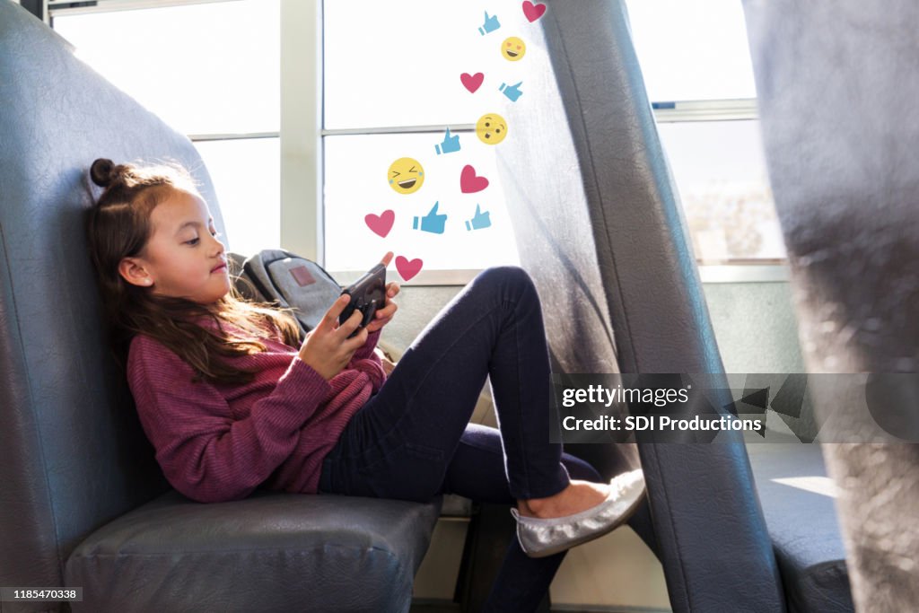 Preteen girl using social media while on school bus