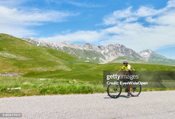 Man is riding a mountain bike on a small road in the mountains on June 12, 2019 in Gran Sasso d'Italia, Italy.