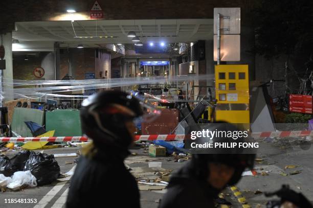 Motorcyclist and pillion rider are seen in front of the entrance to the ransacked Hong Kong Polytechnic University in Hong Kong on November 29, 2019....