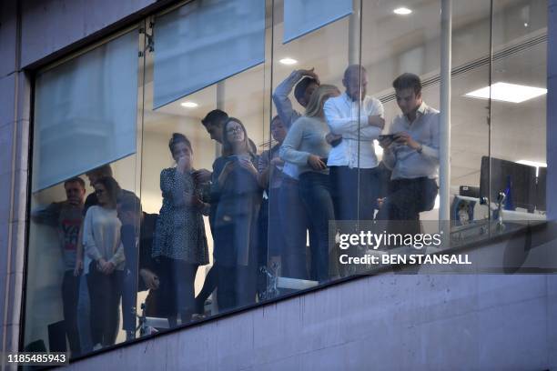 Office workers peer out of the windows of Leadenhall Market near London Bridge in central London, on November 29, 2019 after reports of shots being...