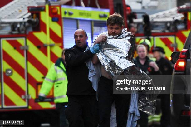 Police assist an injured man near London Bridge in London, on November 29, 2019 after reports of shots being fired on London Bridge. The Metropolitan...