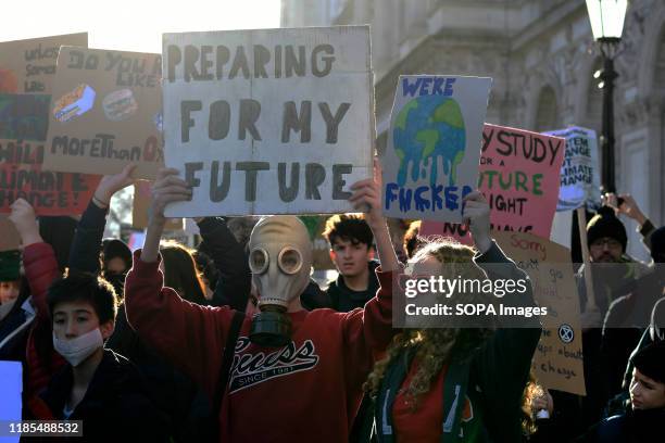 Environmental protester wearing a gas mask while holding a placard during the strike. Children, young people, and adults join together in a strike to...