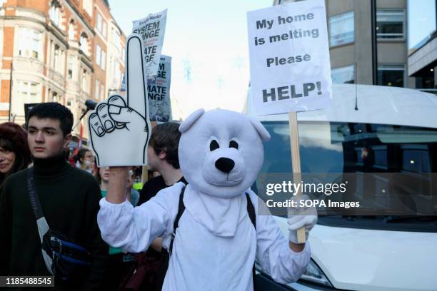 Environmental protester wearing a polar bear costume while holding a placard during the strike. Children, young people, and adults join together in a...