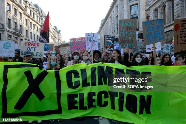 Environmental protesters holding a large banner and placards while shouting slogans during the strike. Children, young people, and adults join...