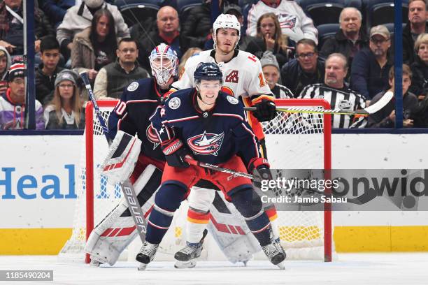 Scott Harrington of the Columbus Blue Jackets battles for position with Matthew Tkachuk of the Calgary Flames in front of goaltender Joonas Korpisalo...