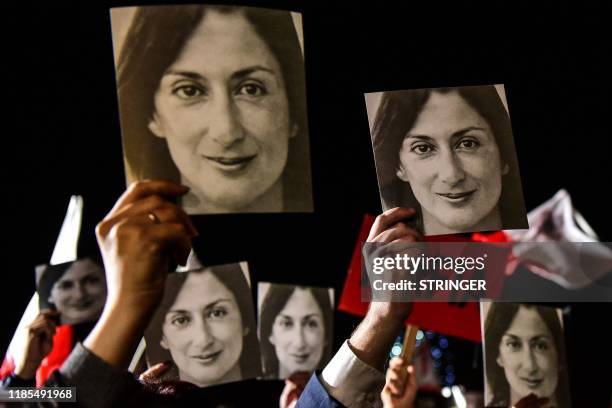 People holding placards reading "Mafia Government" and photos of killed journalist Daphne Caruana Galizia, stage a protest called by Galizia's family...