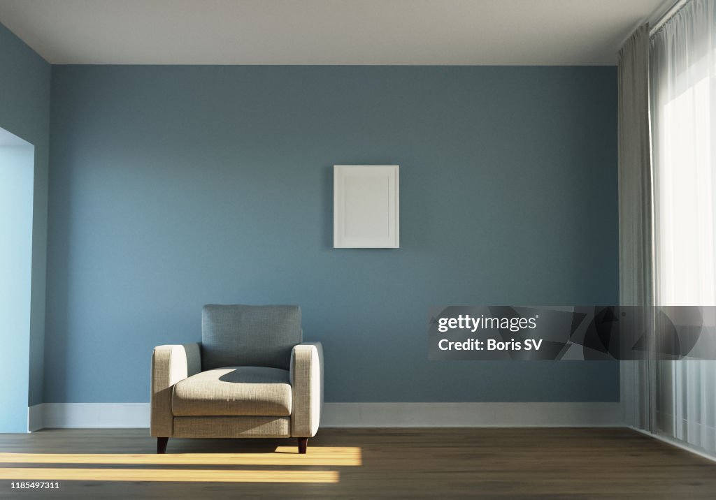 Empty sunlit room with armchair and white picture frame