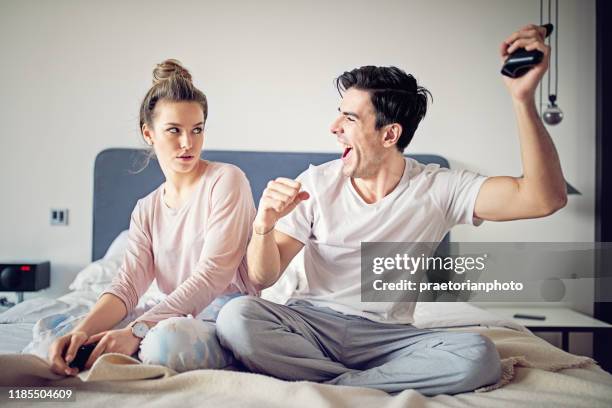 happy couple is playing video games in bed - angry girlfriend stock pictures, royalty-free photos & images