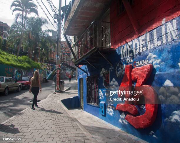 Woman walks past a mural in Commune 13 of Medellin, Colombia on November 29, 2019. Medellin is experiencing an increase in its national and foreign...