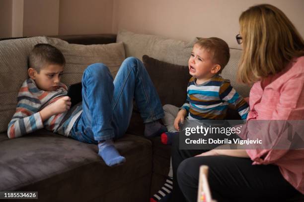 crying toddler at home with his older brother and mother - crying sibling stock pictures, royalty-free photos & images