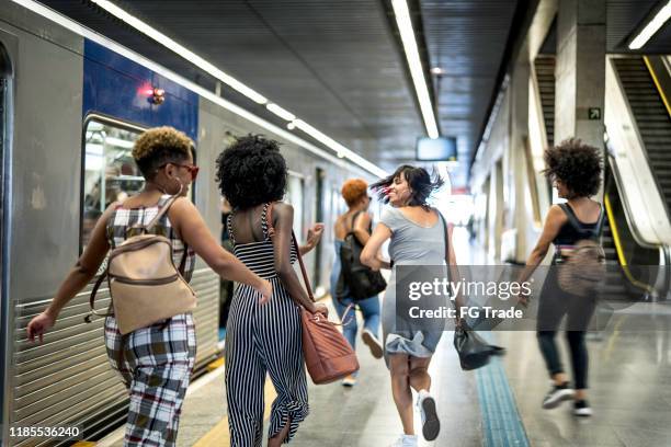 vue arrière d'un groupe de femmes courant pour attraper un train - amis train photos et images de collection