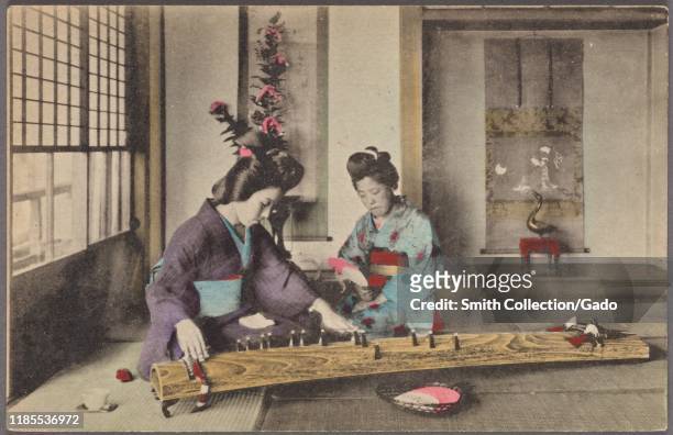 Illustrated postcard of two Japanese women wearing traditional kimono, kneeling on the floor playing the traditional Japanese stringed musical...