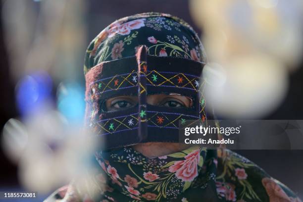 Woman wearing burqa and a patterned particular mask sells her own handiworks and souvenirs for a living in Hormuz Island of Bandar Abbas, Iran on...
