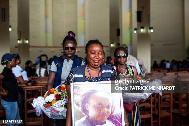 Woman holds a portrait as family and colleagues of Belinda Kasongo who was part of the Ministry of Health vaccination team and was killed by armed...