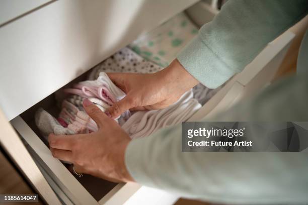 mom folding baby clothes into the drawer - baby clothes stock pictures, royalty-free photos & images
